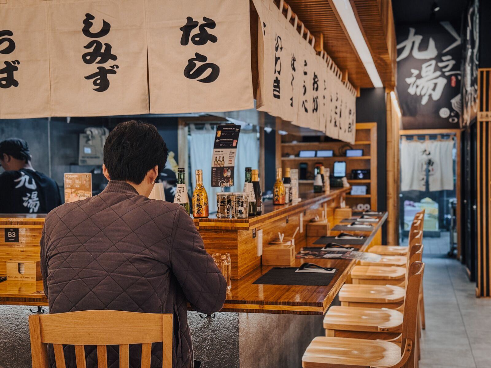 九汤屋 Bowery 店内的原木拉面吧台与日式暖帘